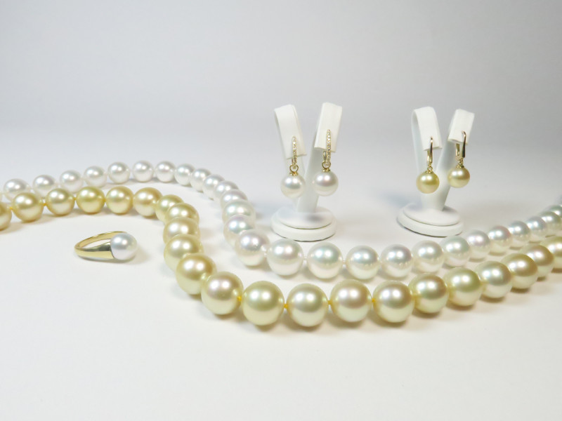 Ein exklusives Schmuckset bestehend aus zwei Suedseeperlenketten in Weiss und Champagner mit dazu passenden Perlenohrringen und einem eleganten Ring.