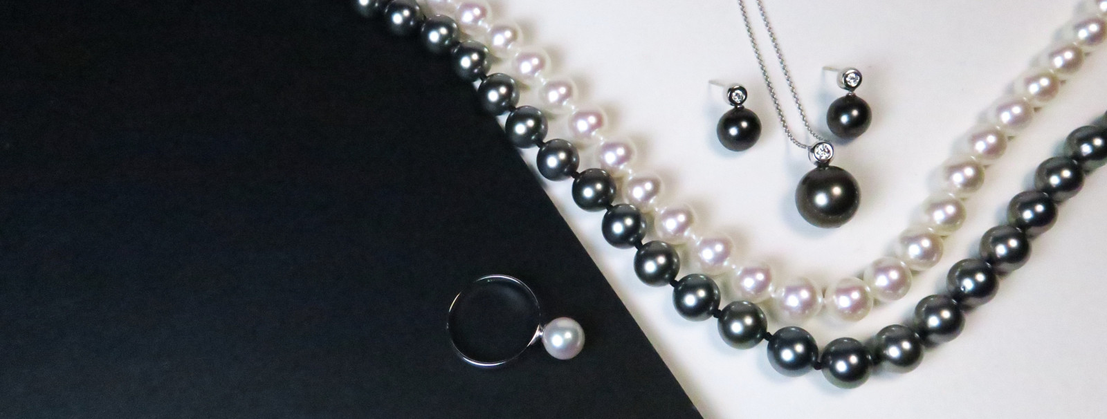 Perlenluxus in allen Facetten – Unsere Perlenschmuck-Kollektion Exklusiver echter Perlenschmuck der gesamten Kollektion mit handverlesenen Perlenketten, Ringen und Ohrringen vor edlem, dunklem Hintergrund.