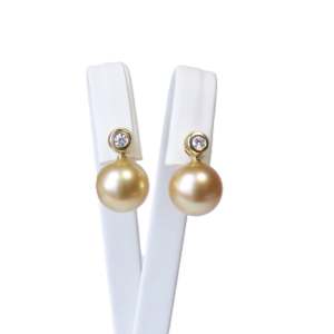 Goldene Südseeperlen-Ohrstecker an 14k Gelbgold mit Diamanten, präsentiert auf einem Ohrständer in der Frontansicht.