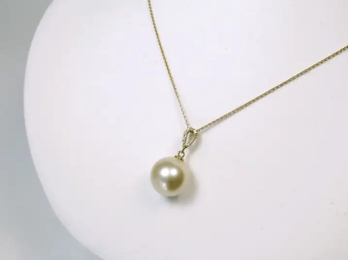Großer champagnerfarbener Südseeperlen-Anhänger an einer Gelbgoldkette, präsentiert auf einer Schmuckbüste von halb rechts.