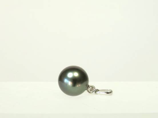 Makelloser Tahitiperlen-Anhänger (11,4 mm) mit einem funkelnden 0,04ct Diamanten auf der rechten Bildseite liegend fotografiert.